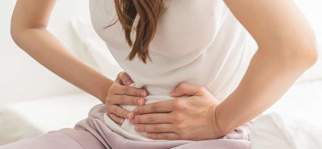 Mujer con dolores menstruales aplicando calor Mujer con dolores menstruales aplicando calor
