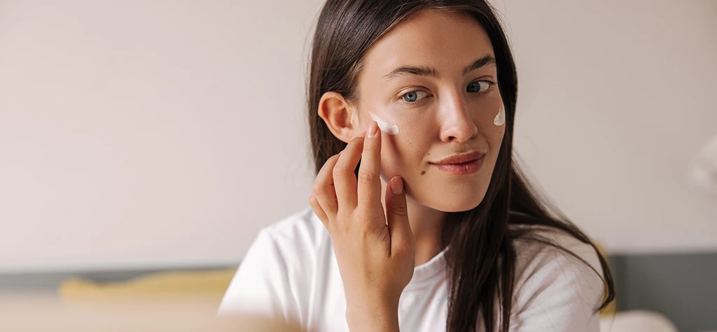 Mujer aplicando protector solar facial en el rostro